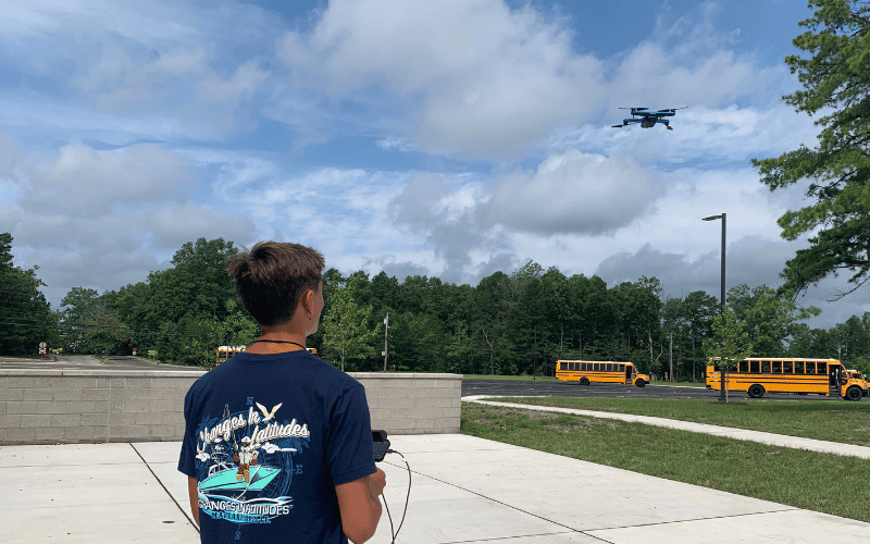Student flying a drone on a school campus