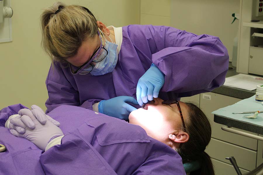A Burlington County adult education student looks inside a peer’s mouth to practice as a dental hygienist/assistant.