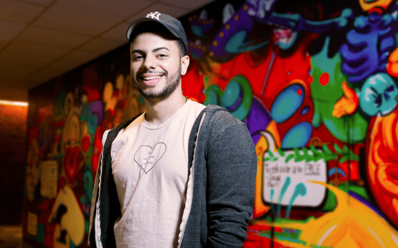 Billy Torres, a 2015 graduate of the computer science program at Bergen County Technical Schools, poses in front of a mural.