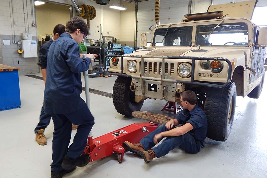 Three BCIT students work to repair a Hummer.