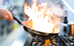 a frying pan with fire in it on the stove