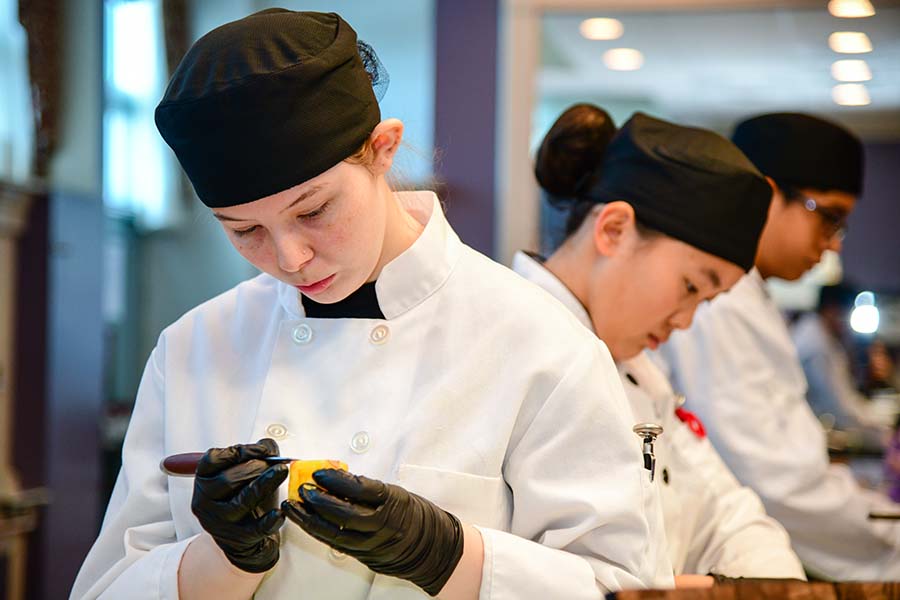 A Passaic County culinary student carefully prepares a food item.