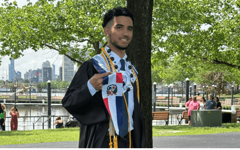 Eric Jimenez stands in his graduation cap and gown