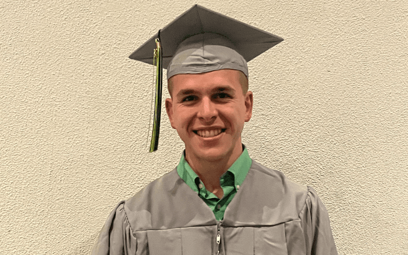 Owen Demeter standing in his cap and gown at graduation.