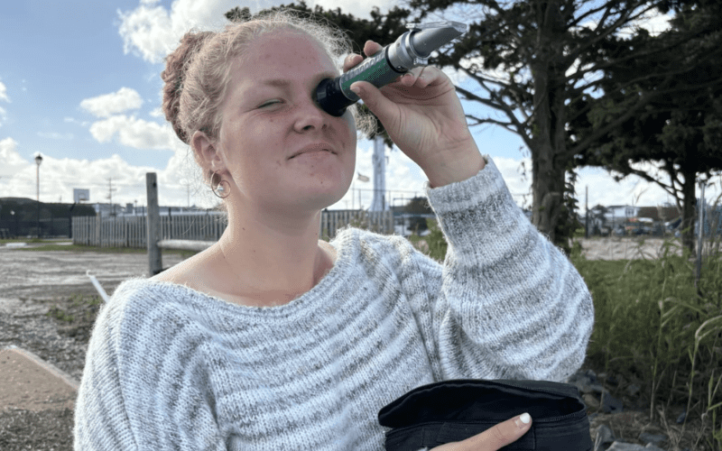 A student uses a refractometer to test the salinity of the water. 