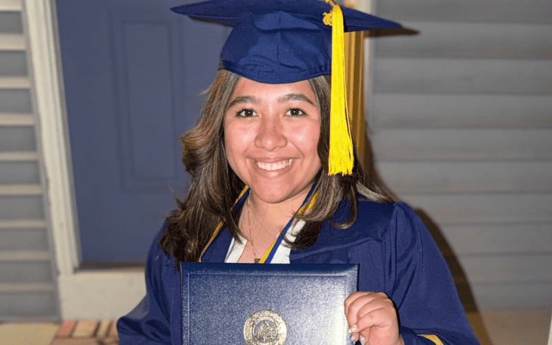 Student holding diploma cap and gown
