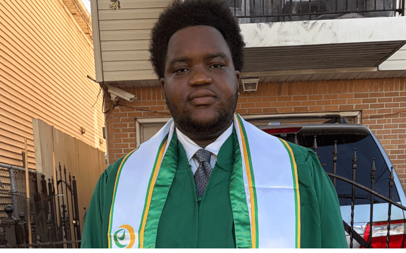 Student standing outside in gown graduation