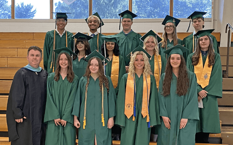 Olivia and her classmates standing in their cap and gowns