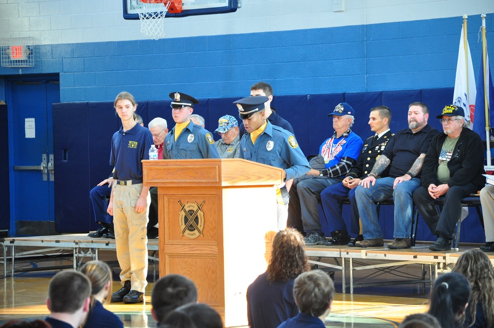 A Warren County student gives a speech in front of veterans in a crowded gym.