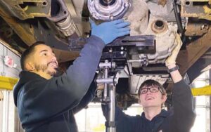 Miguel Rosario helps Eric Krise fix a car